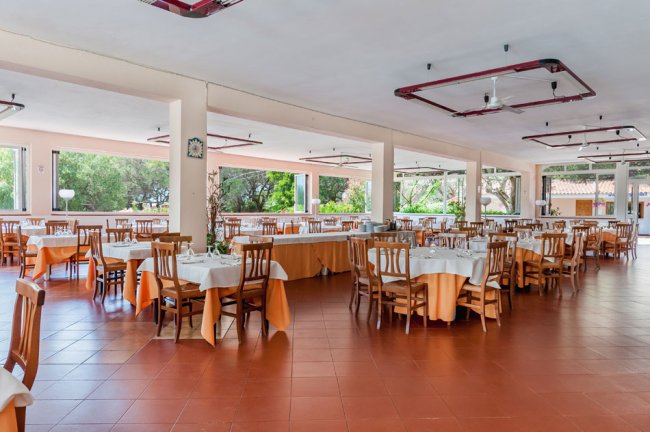 Sala ristorante spaziosa con tavoli apparecchiati di arancione e bianco.