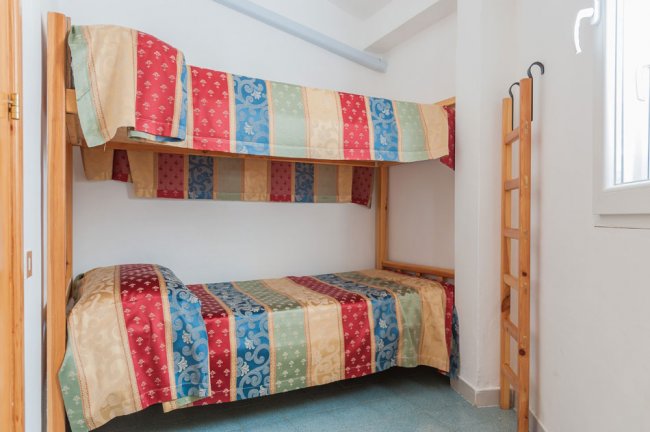 Stanza con letto a castello e coperte a righe multicolori.