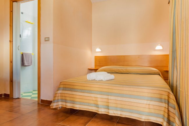 Camera da letto con letto matrimoniale, lenzuola a righe e asciugamani piegati.