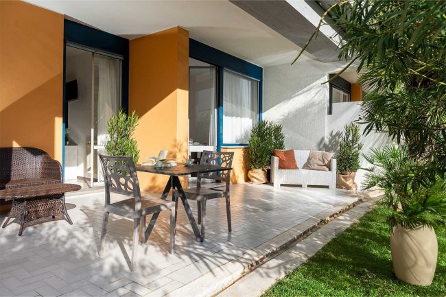 Patio esterno con mobili eleganti e piante in vaso.