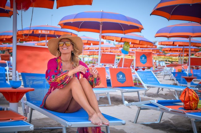 Donna seduta sotto ombrelloni colorati in spiaggia.