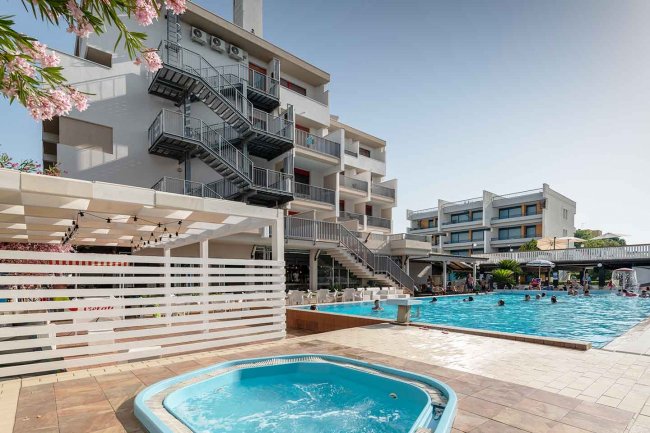 Idromassaggio e piscina esterna di un hotel moderno con scale antincendio.