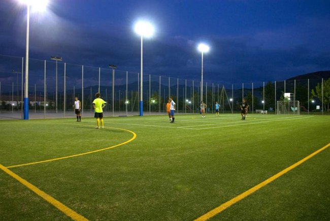 Persone giocano a calcio su un campo illuminato di notte.