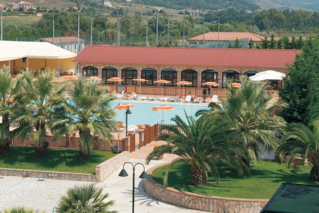 Piscina circondata da palme e ombrelloni arancioni.