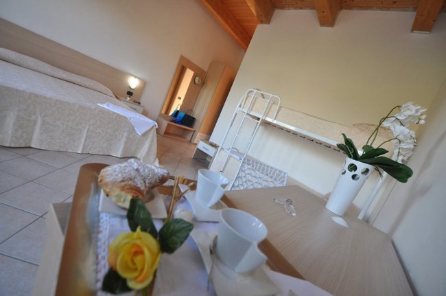 Un accogliente camera da letto con letto matrimoniale, fiori e colazione su un tavolo.