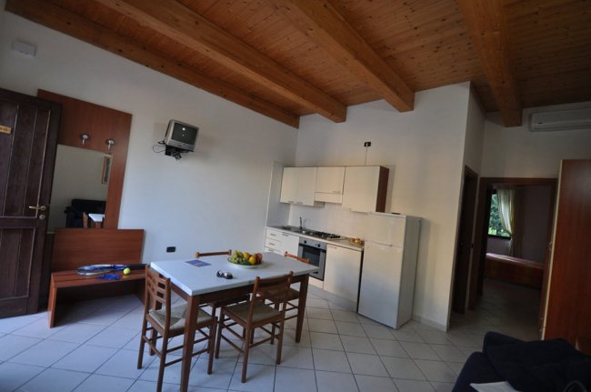 Una cucina moderna con tavolo da pranzo, mobili bianchi e soffitto con travi in legno.