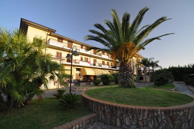 Edificio residenziale con palme e giardino curato.