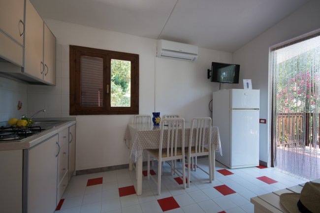 Cucina luminosa con tavolo da pranzo, frigorifero e accesso esterno.