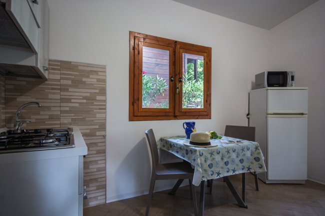 Cucina con finestra, tavolo apparecchiato e frigorifero.