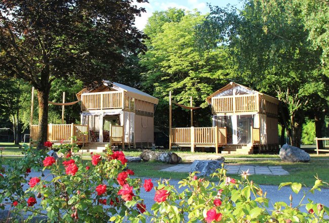 Due capanne in legno in un giardino fiorito.
