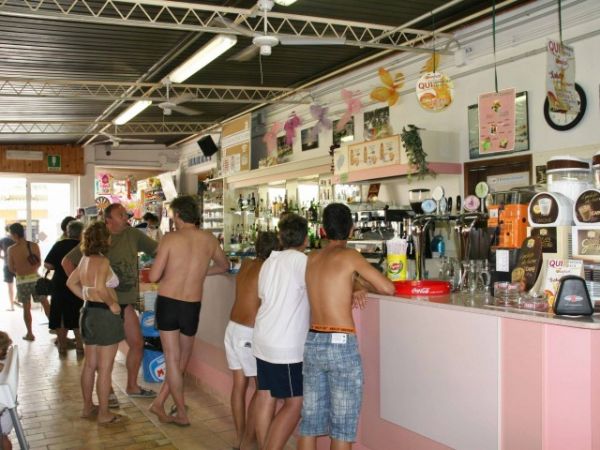 Interno di un bar affollato con persone al bancone.