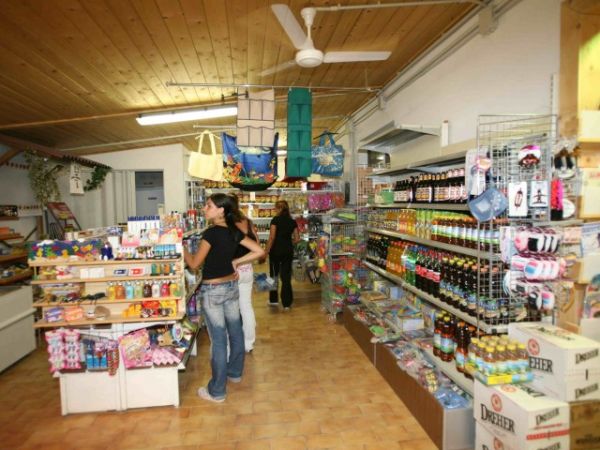 Interno di un negozio con scaffali pieni di prodotti e persone che fanno acquisti.