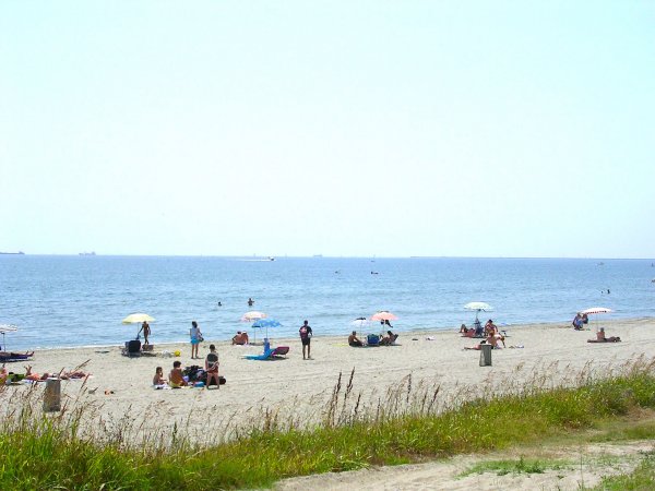Una spiaggia sabbiosa con persone sotto gli ombrelloni vicino al mare.