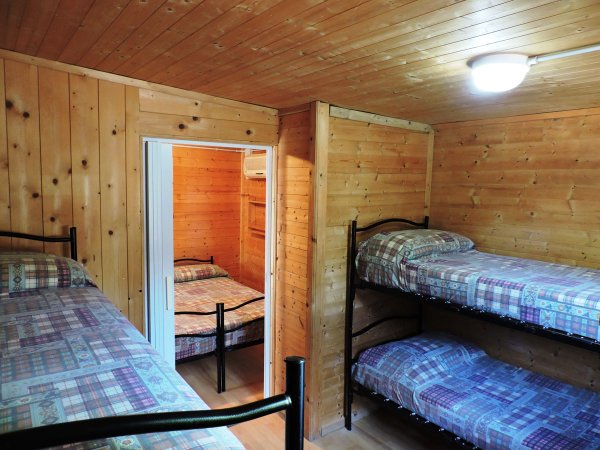Interno di una camera con letti a castello e pareti in legno.