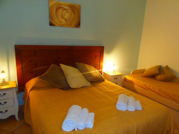 Camera con letto matrimoniale, lenzuola gialle, luci soffuse.