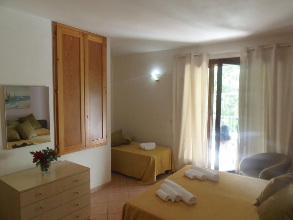 Camera da letto con letti gialli, cassettiera chiara, armadio a muro e accesso al balcone.