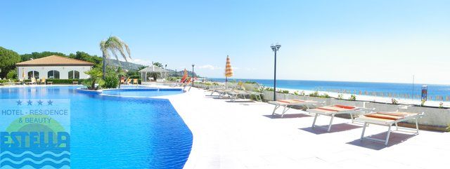 Piscina all'aperto con lettini, vista sul mare e cielo sereno.