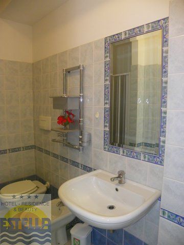 Un bagno con lavabo bianco, specchio rettangolare e piastrelle con bordi blu.