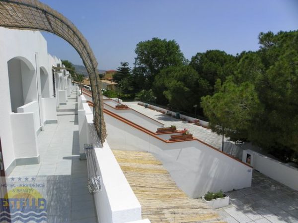 Terrazzino con pavimento bianco, piante, e vista su alberi verdi.