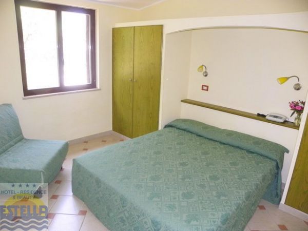 Stanza d'albergo con letto matrimoniale, divano e armadio verde.