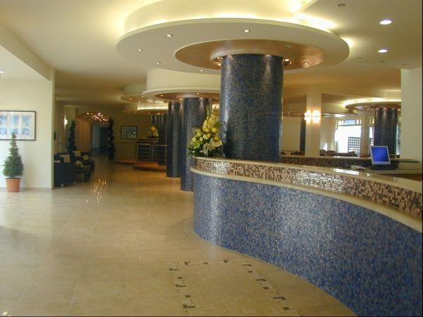 Un'elegante hall d'albergo con colonne blu e un bancone con mosaico.