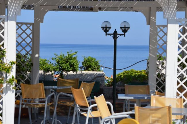 Gazebo con sedie gialle vista mare, lampione nero al centro.