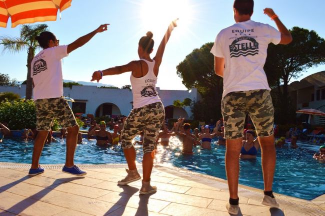 Tre animatori intrattengono vicino a una piscina soleggiata.