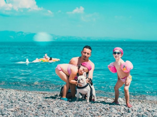 Persona con due bambini e un cane sulla spiaggia.