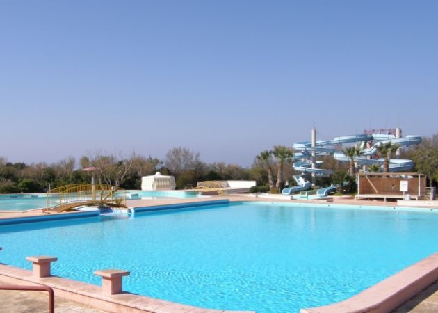 Una grande piscina con scivoli e un cielo blu.