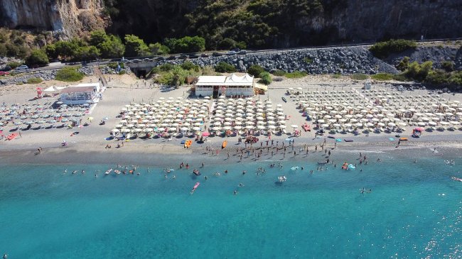 Spiaggia affollata con ombrelloni e mare blu.