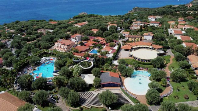 Veduta aerea di un villaggio turistico con piscine e verde.