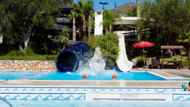 Una piscina con scivoli d'acqua e spruzzi al centro.