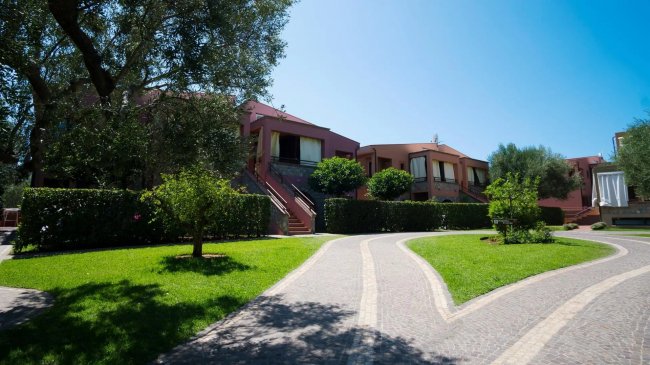 Sentiero tra edifici residenziali e giardini.