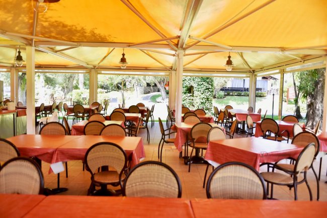 Sala da pranzo con tavoli coperti da un tendone giallo.
