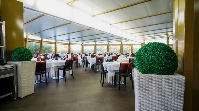 Ampia sala da pranzo con tavoli apparecchiati.