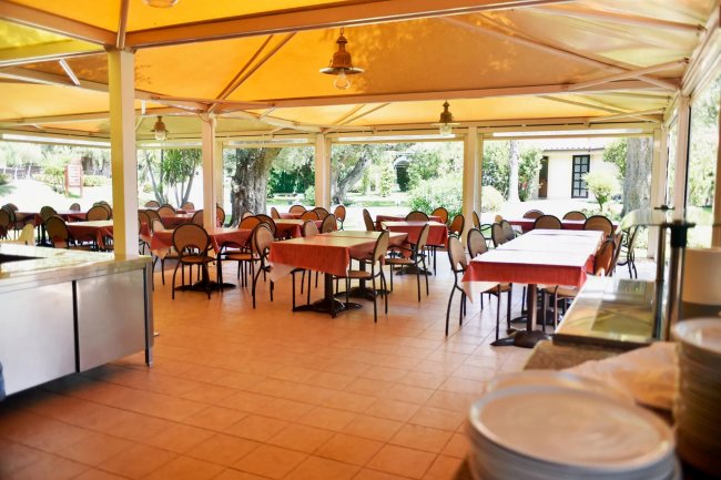Sala da pranzo esterna con tavoli coperti.