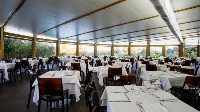 Ristorante con tavoli apparecchiati e sedie marroni.