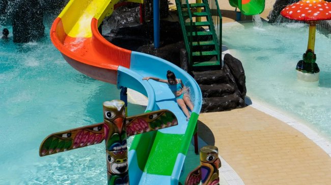 Scivolo colorato in un parco acquatico con bambino.