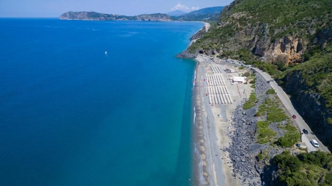 Costa azzurra con spiaggia e strada costiera.