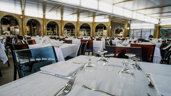 Ristorante elegante con tavoli apparecchiati e sedie in vetro.