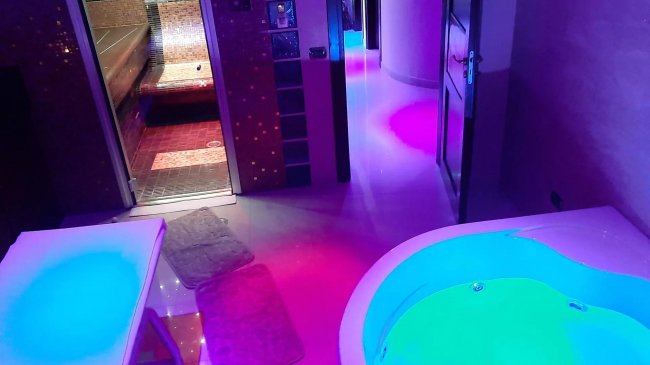 Spa con vasca idromassaggio e sauna in uno spazio colorato.