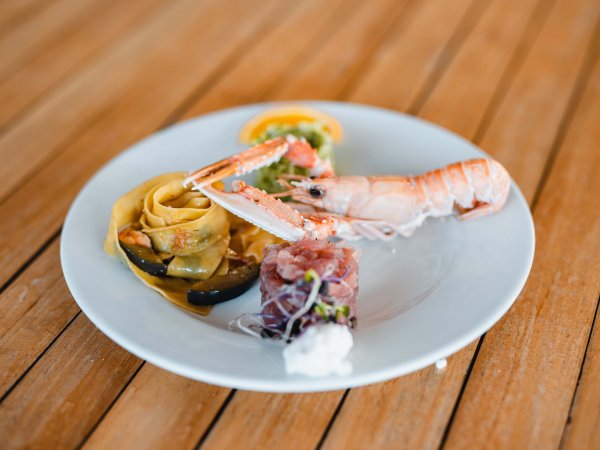 Piatto di pasta e frutti di mare su tavolo di legno.