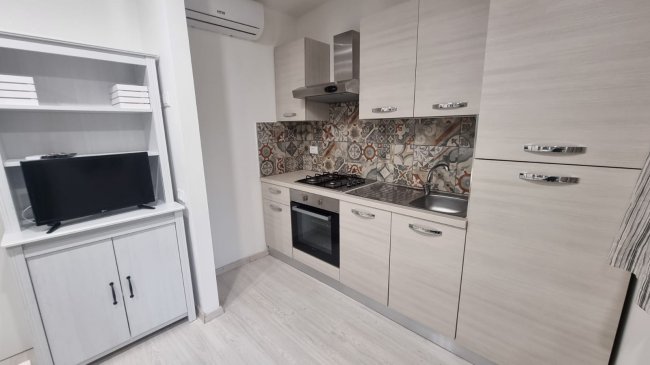Cucina moderna con piastrelle colorate e mobili chiari.