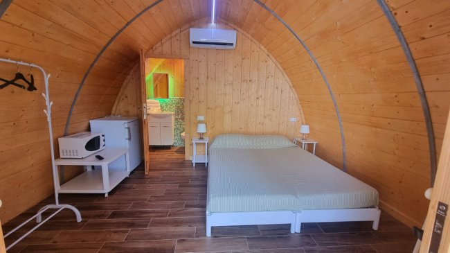 Interno di una cabina in legno con letto matrimoniale e angolo cottura.