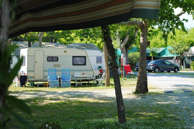 Camper parcheggiato in un campeggio con sedie pieghevoli davanti.