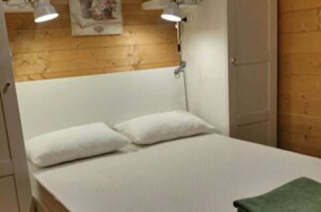 Camera con letto matrimoniale, pareti in legno chiaro.