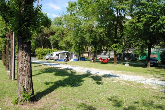 Area campeggio con roulotte, amaca e alberi verdi.