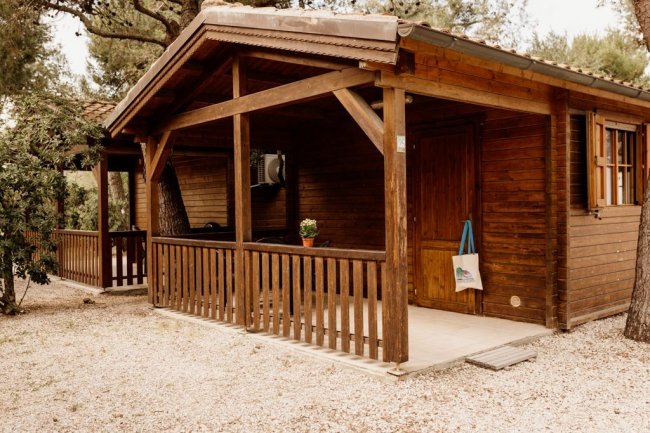 Casetta di legno con veranda e recinzione con cancello.