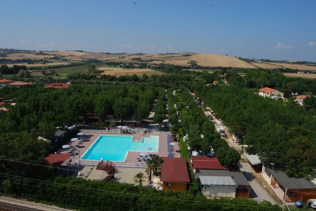 Piscina all'aperto circondata da alberi e colline sullo sfondo.