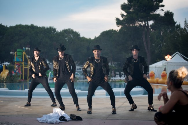 Gruppo di persone balla davanti a una piscina all'aperto.
